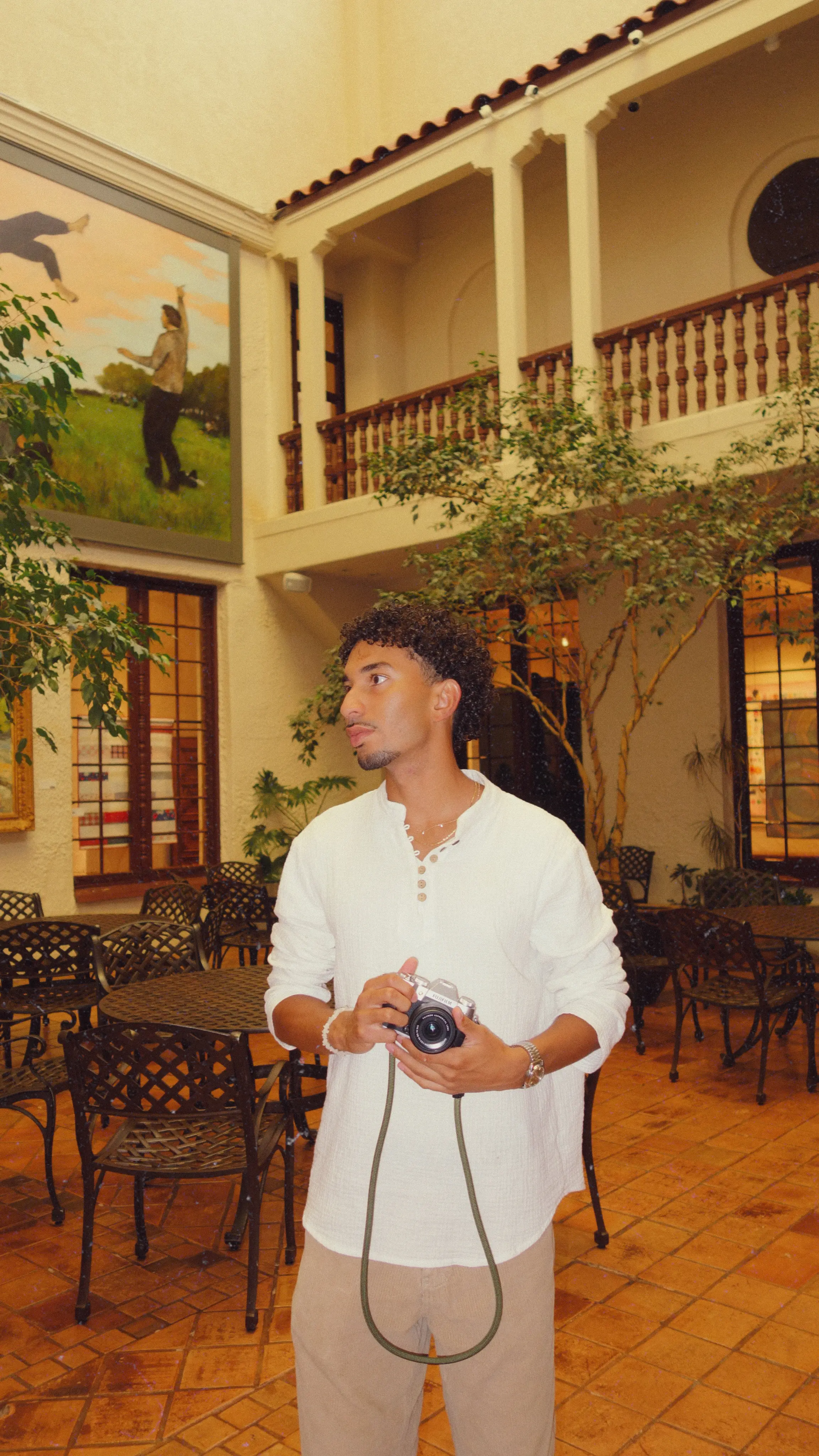 Joshua Barrera holding a Fujifilm camera in a courtyard